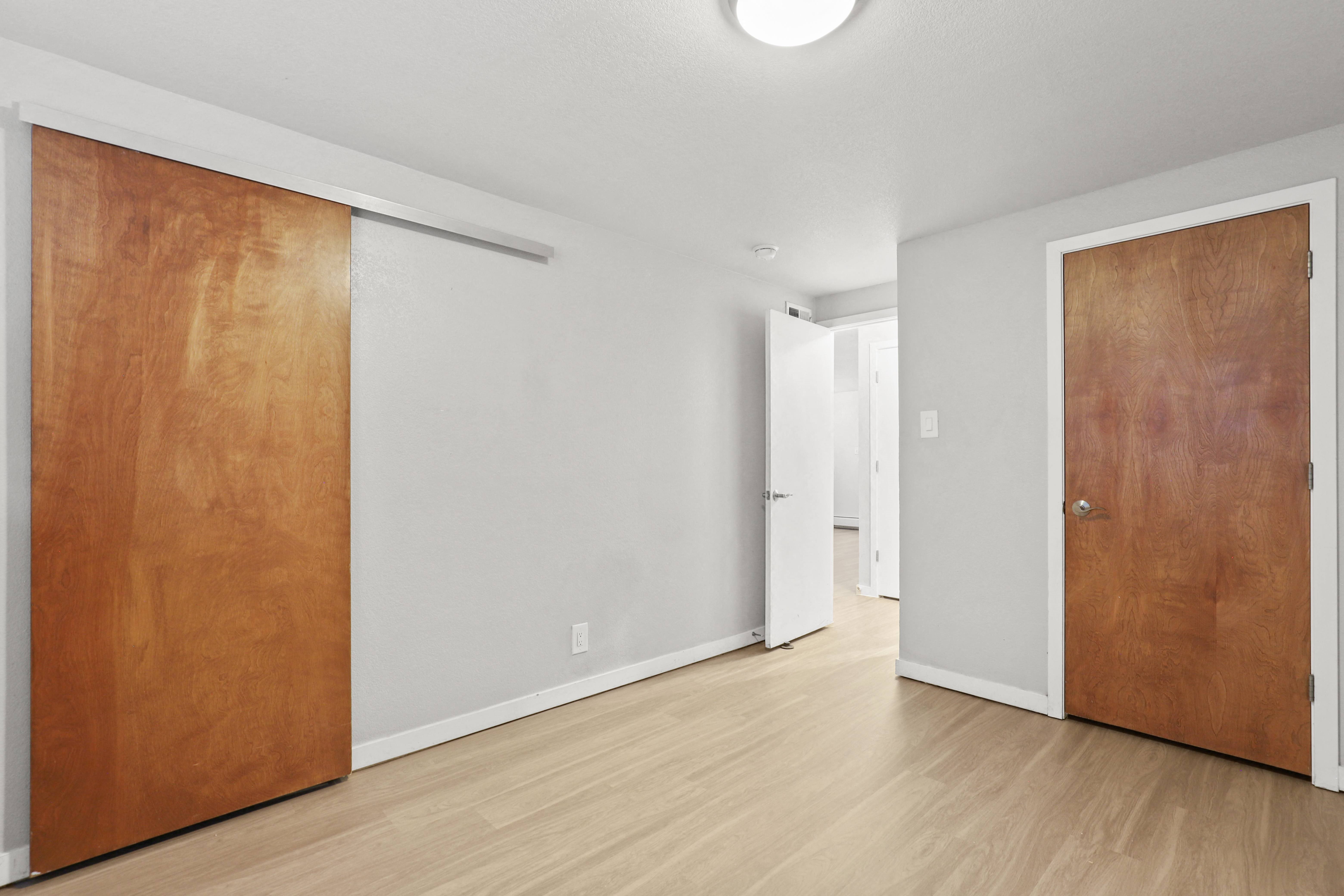 an empty room with a wooden door and a white wall